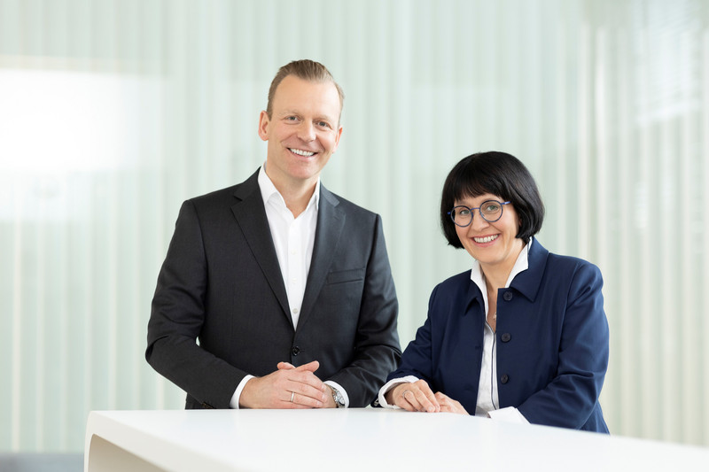Anja Zschernig und PARI Group CEO Arne W. Dirks lächelt vor einem Tisch stehend