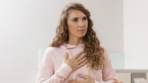 Bronchiektasen-Therapie und Behandlung: Tipps für Betroffene Junge Frau hält sich die Hände an die Brust