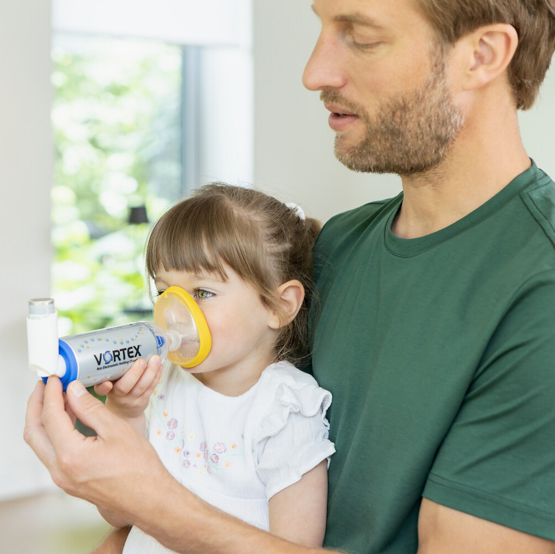 Father helping daughter with inhaling asthma spray with the VORTEX spacer