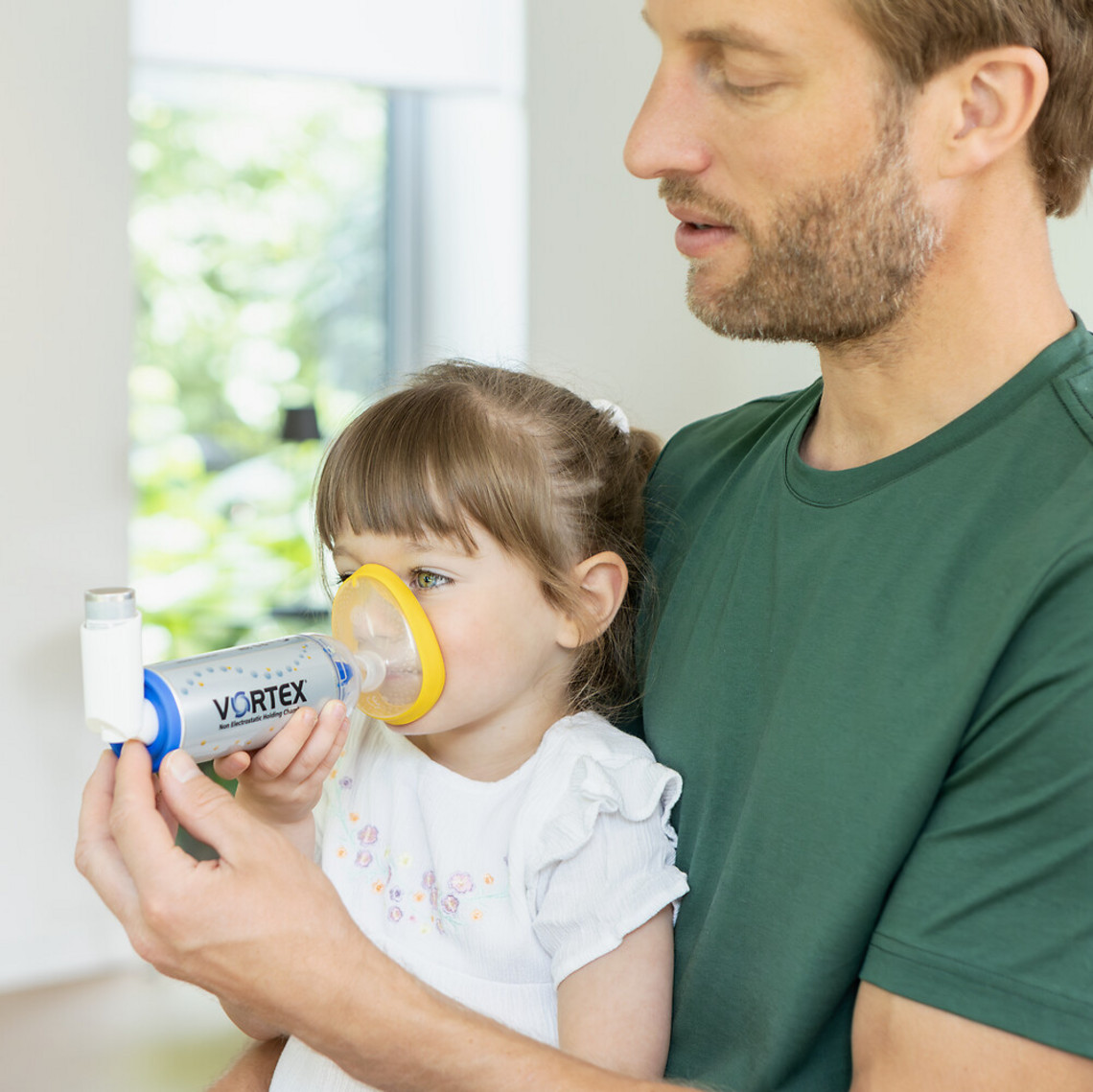 Asthma bei Kindern: Nebenwirkungen von Asthmaspray vermeiden Vater hilft Tochter bei der Inhalation von Asthmaspray mit VORTEX Inhalierhilfe