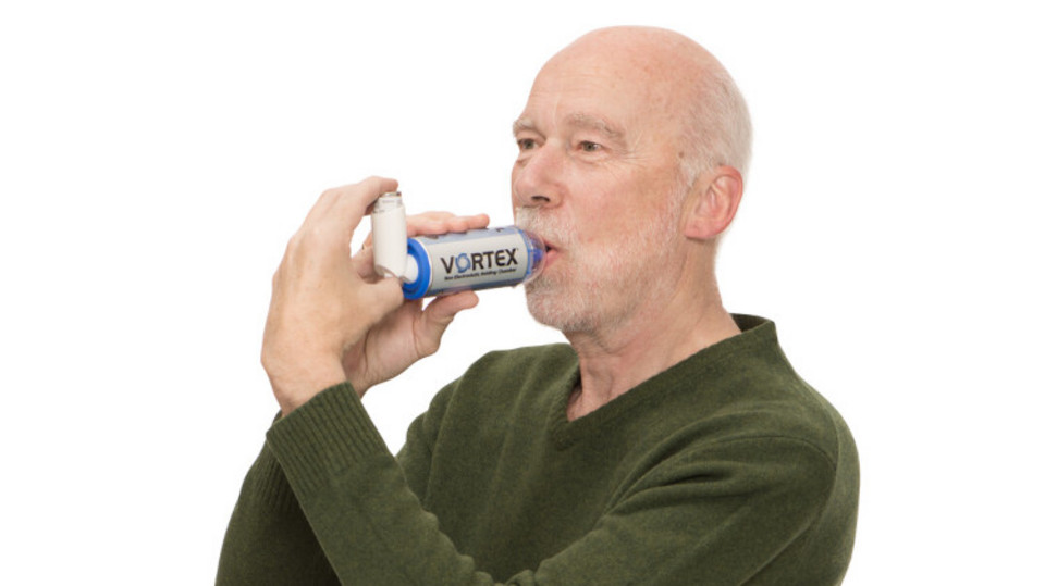 Man inhales asthma spray with spacer