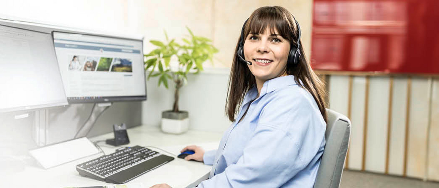 Eine Servicemitarbeiterin von PARI sitzt mit einem Headset vor einem Computer und berät telefonisch einen Kunden