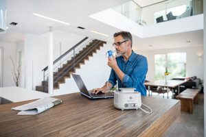 Man works on the laptop and inhales on the side