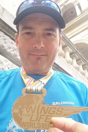 Bernhard hält Medaille vom Wings4Life Run in die Kamera