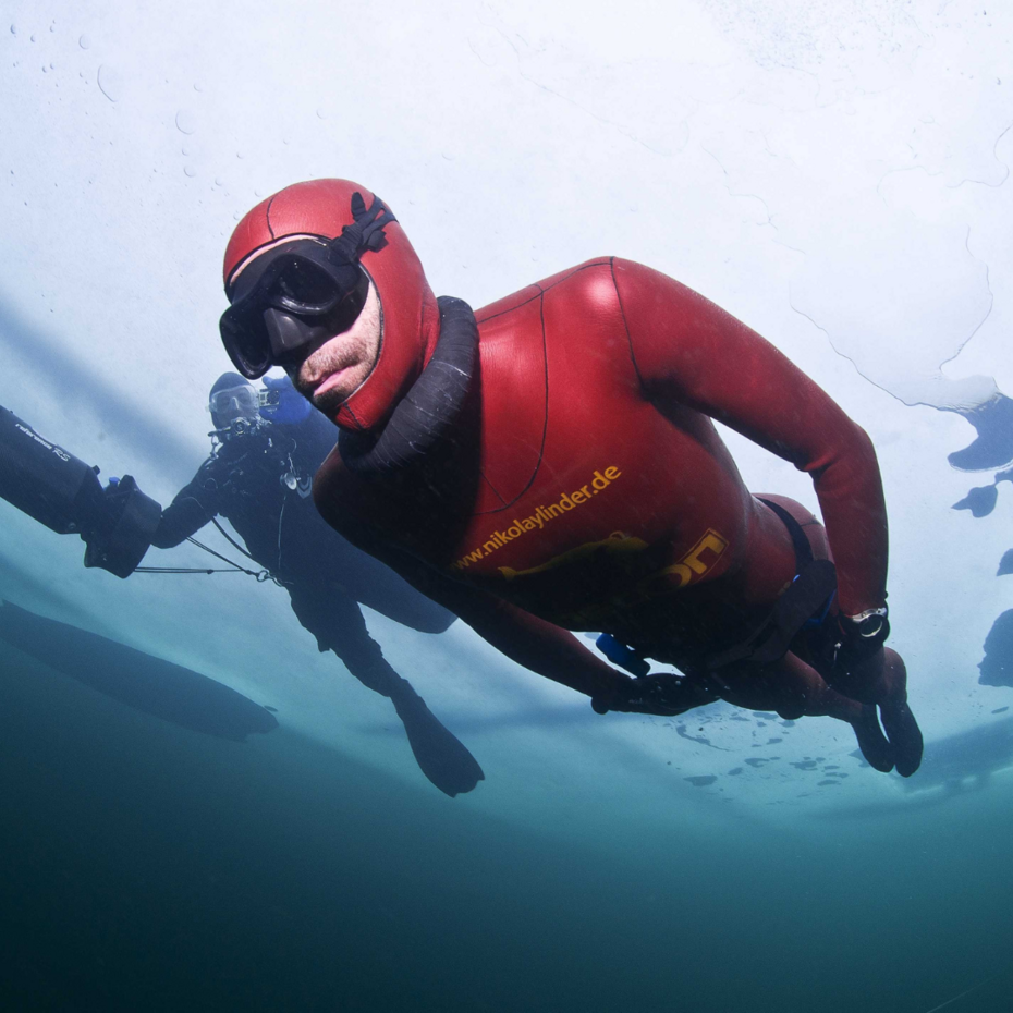 Taucher taucht unter einer Eisschicht entlang