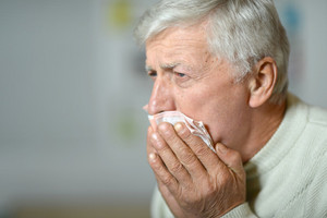 Elderly man coughs into handkerchief