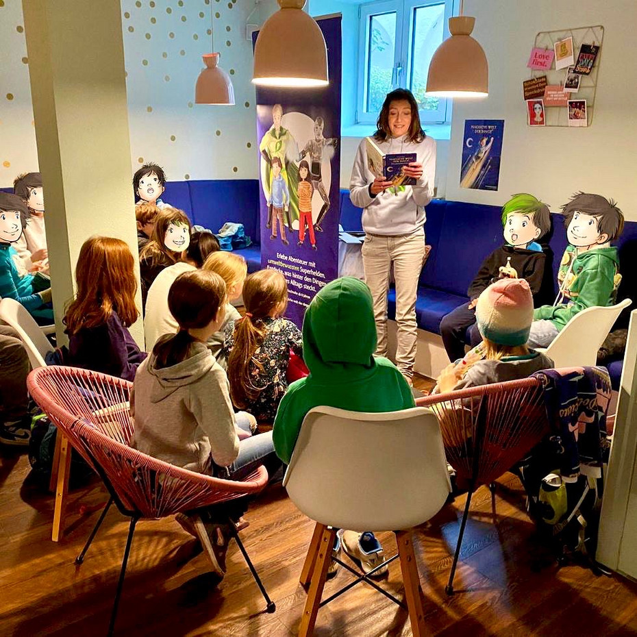 Author Alexandra Wagner reads from her book in a café, children sit in front of her and listen intently