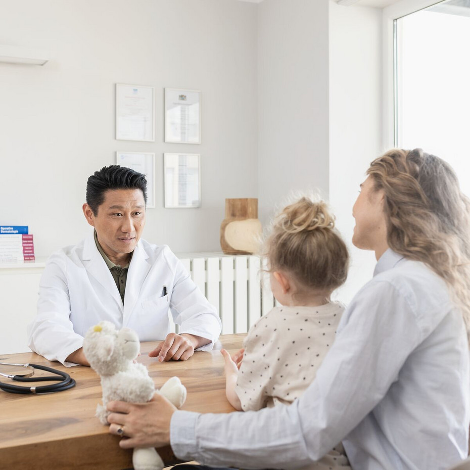 Calming irritated bronchial tubes: Go to the doctor The doctor sits on one side of his desk, talking to a mother who has her daughter on her lap, and on the other side of the desk sits