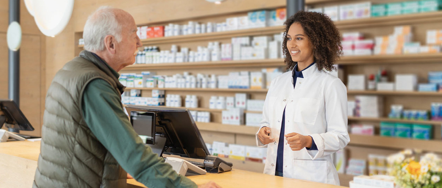Eine Apothekerin berät in einer Apotheke einen älteren Kunden