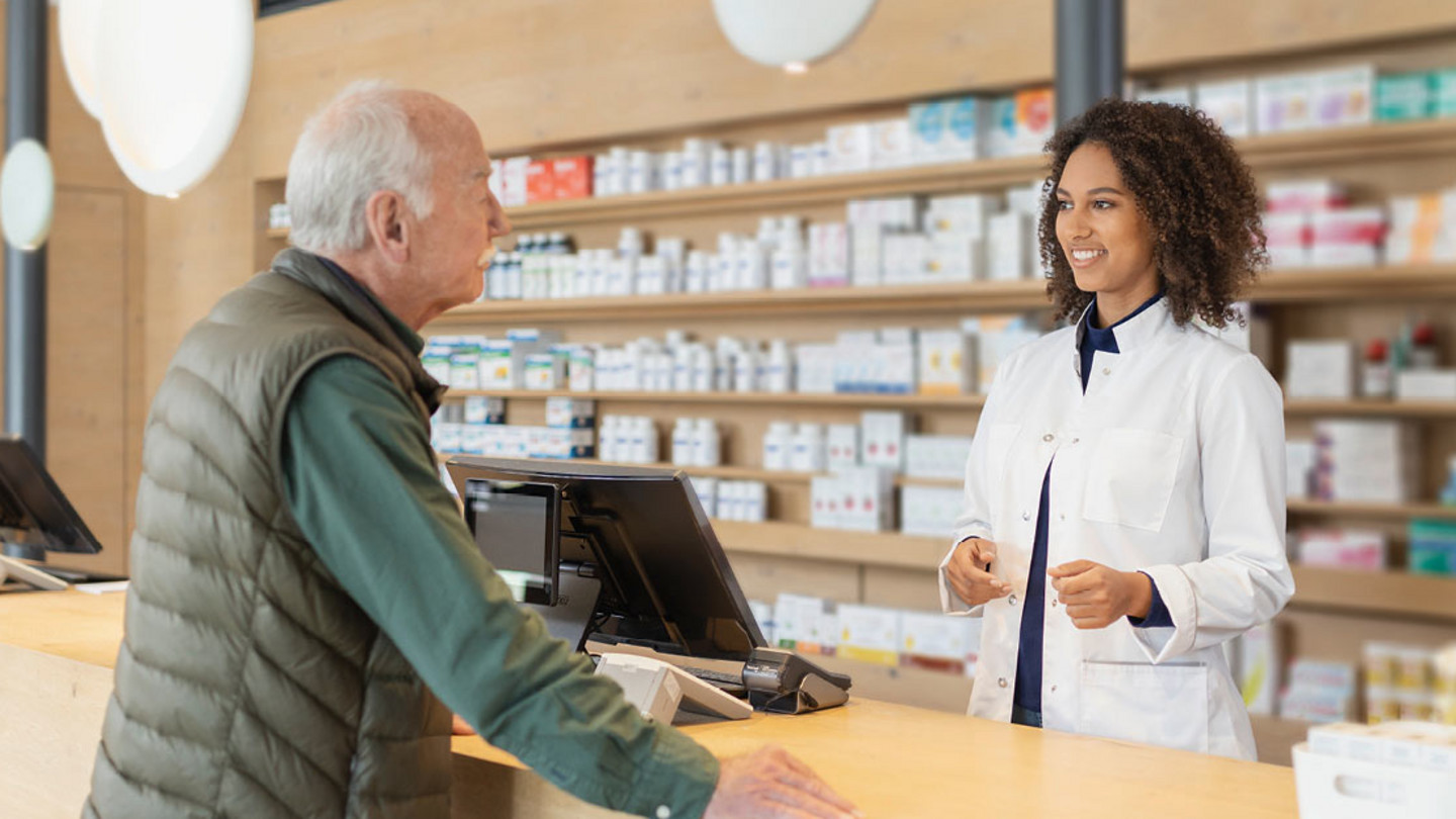 Eine Apothekerin berät in einer Apotheke einen älteren Kunden