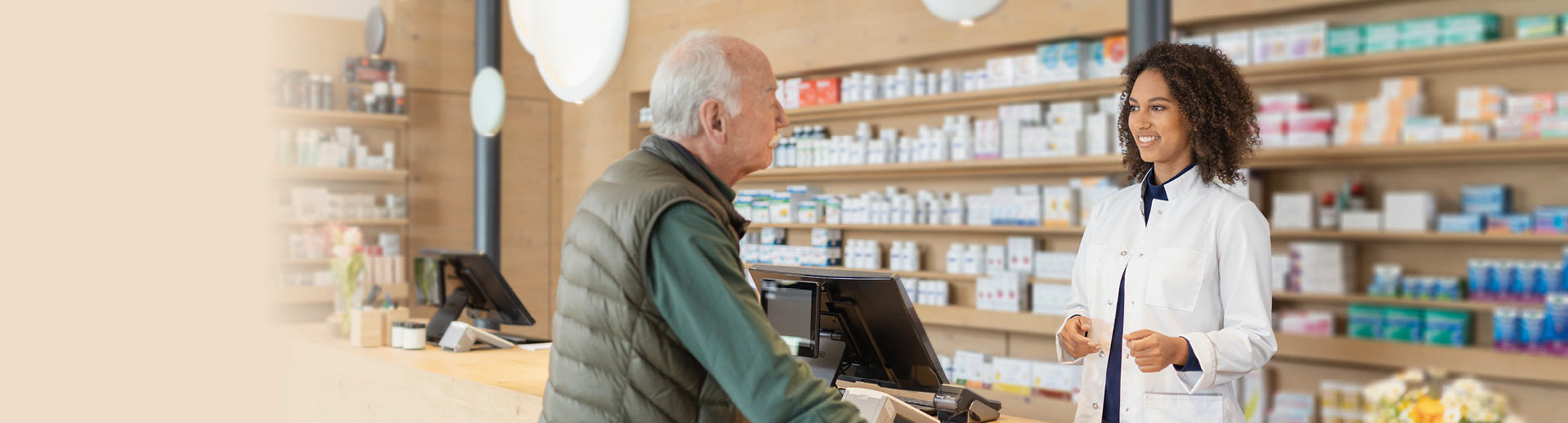 Eine Apothekerin berät in einer Apotheke einen älteren Kunden