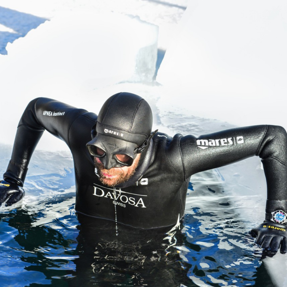 Taucher stützt sich auf dem Rand eines Eislochs ab