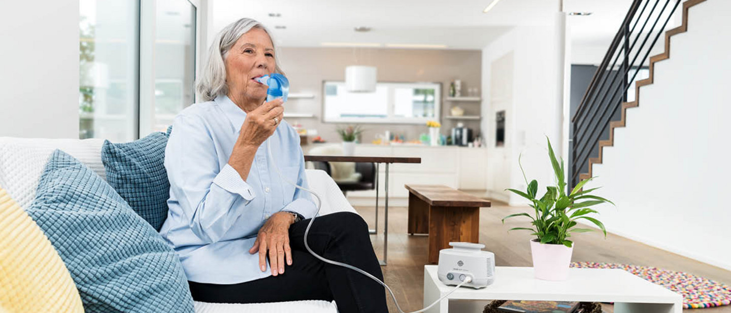  woman fills the nebuliser of a PARI BOY Junior with PARI Protect inhalation solution in a modern kitchen.