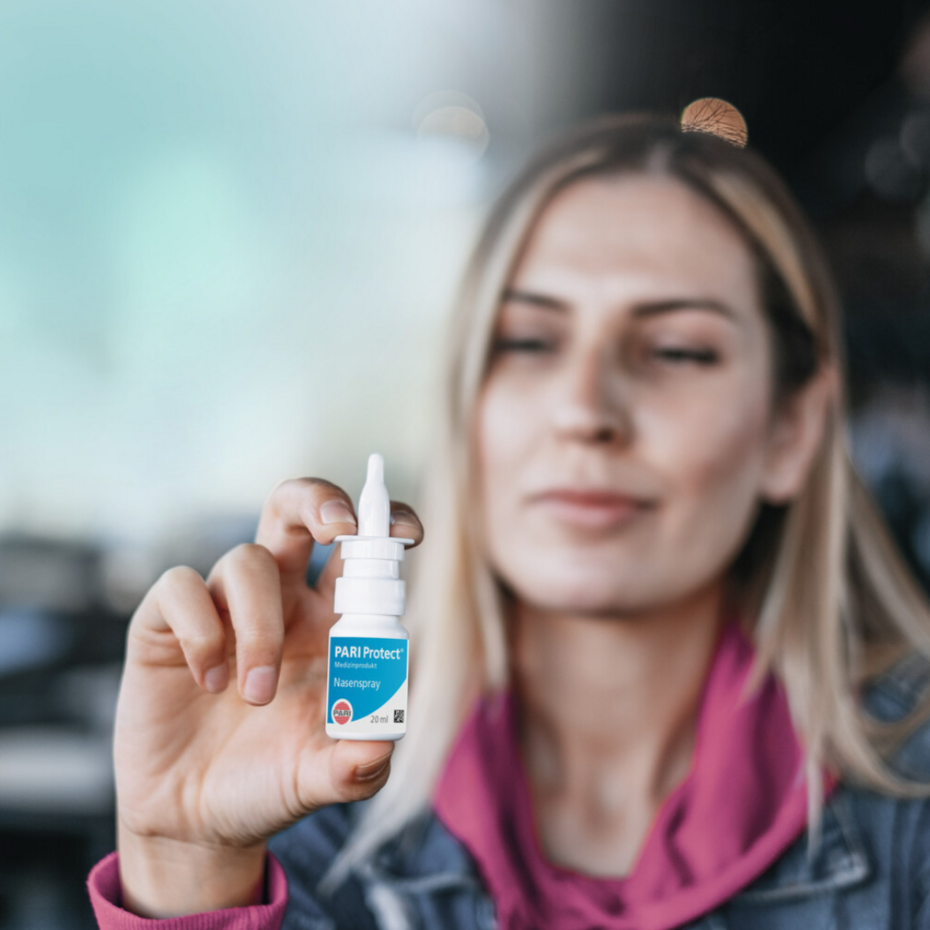 Neugeborenes hat Schnupfen: Nasenspray PARI Protect Junge Frau hält Nasenspray PARI Protect in die Kamera