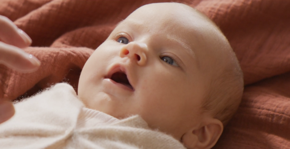 Baby liegt auf einer Decke und blickt nach oben; Nahaufnahme von Gesicht und Oberkörper. Baby liegt auf einer Decke und blickt nach oben; Nahaufnahme von Gesicht und Oberkörper.