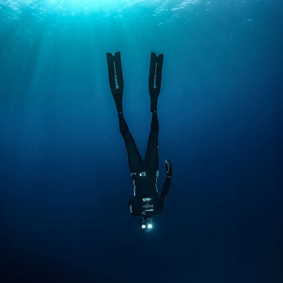 Totale eines Tauchers, der kopfüber im Wasser hängt