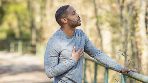 Jogger takes a break, one hand resting on his chest