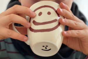 Close-up of a child holding cup in front of face