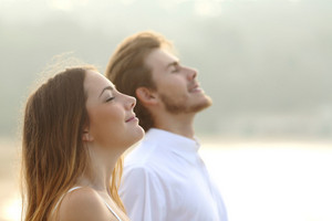 Young woman in foreground and young man in background breathing relaxed through nose