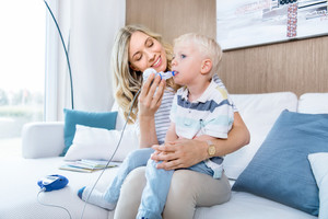 Mother helps her child inhale while sitting on the couch