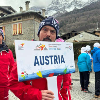 Mann in Nahaufnahme, er hält ein Schild mit der Aufschrift Austria in der Hand