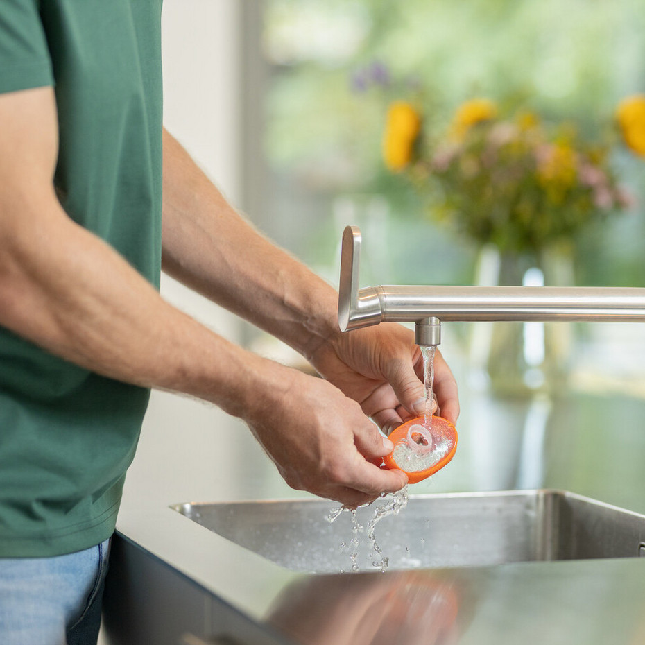 Reinigung der Inhalierhilfe: mit klarem Wasser abspülen Nahaufnahme von Händen, die Kindermaske der VORTEX Inhalierhilfe am Wasserhahn abspülen