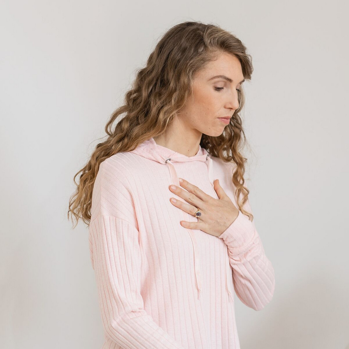 Young woman breathes in deeply, one hand on her chest