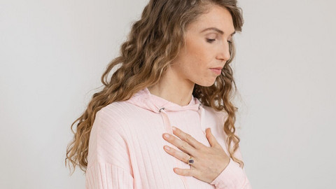Young woman breathes in deeply, one hand on her chest