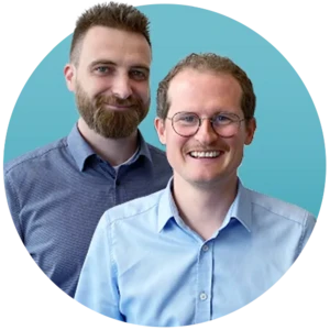 Two smiling men in a blue circle. The central man wears glasses and a light blue shirt. The man on the left has a beard and a blue patterned shirt.