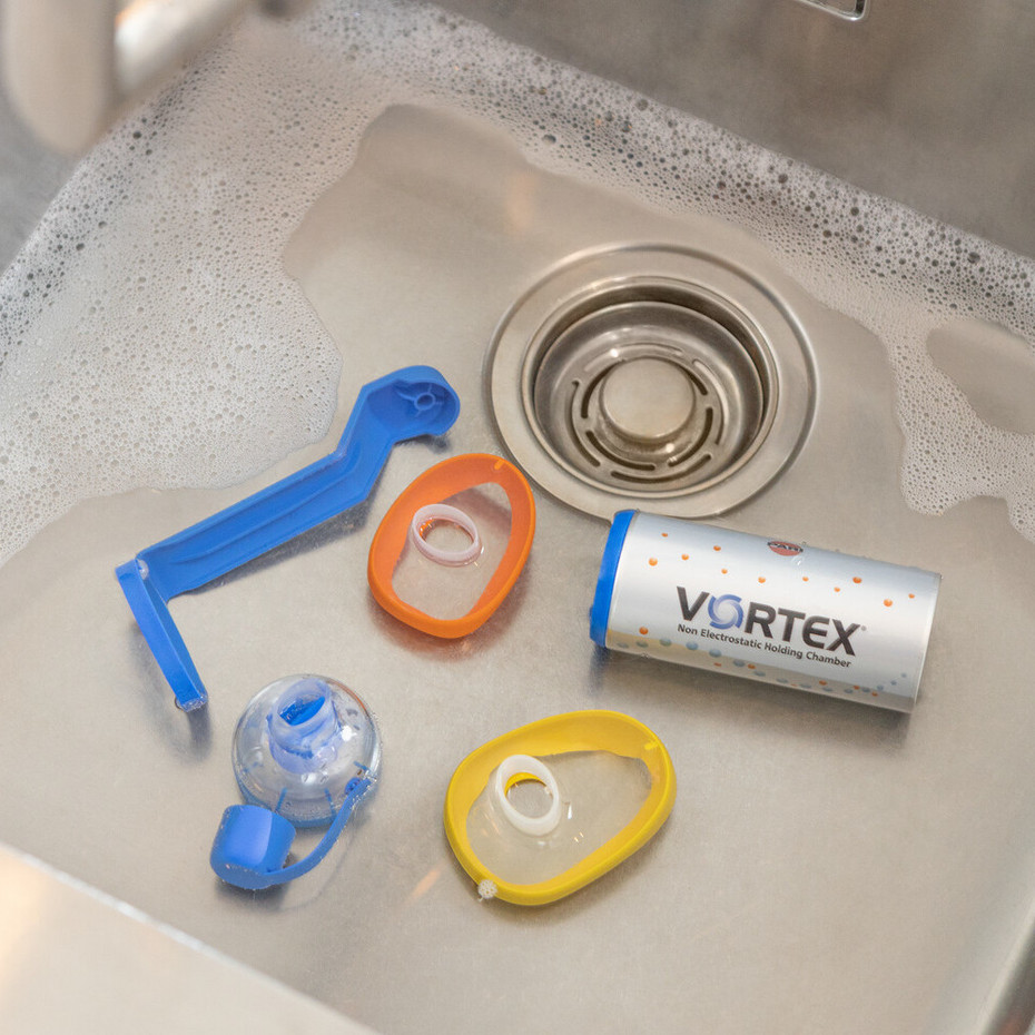 Reinigung der Inhalierhilfe: Wasser mit Spülmittel Aufnahme eines Waschbeckens von oben, es befindet sich Wasser mit Spülmittel und alle Teile der VORTEX Inhalierhilfe darin