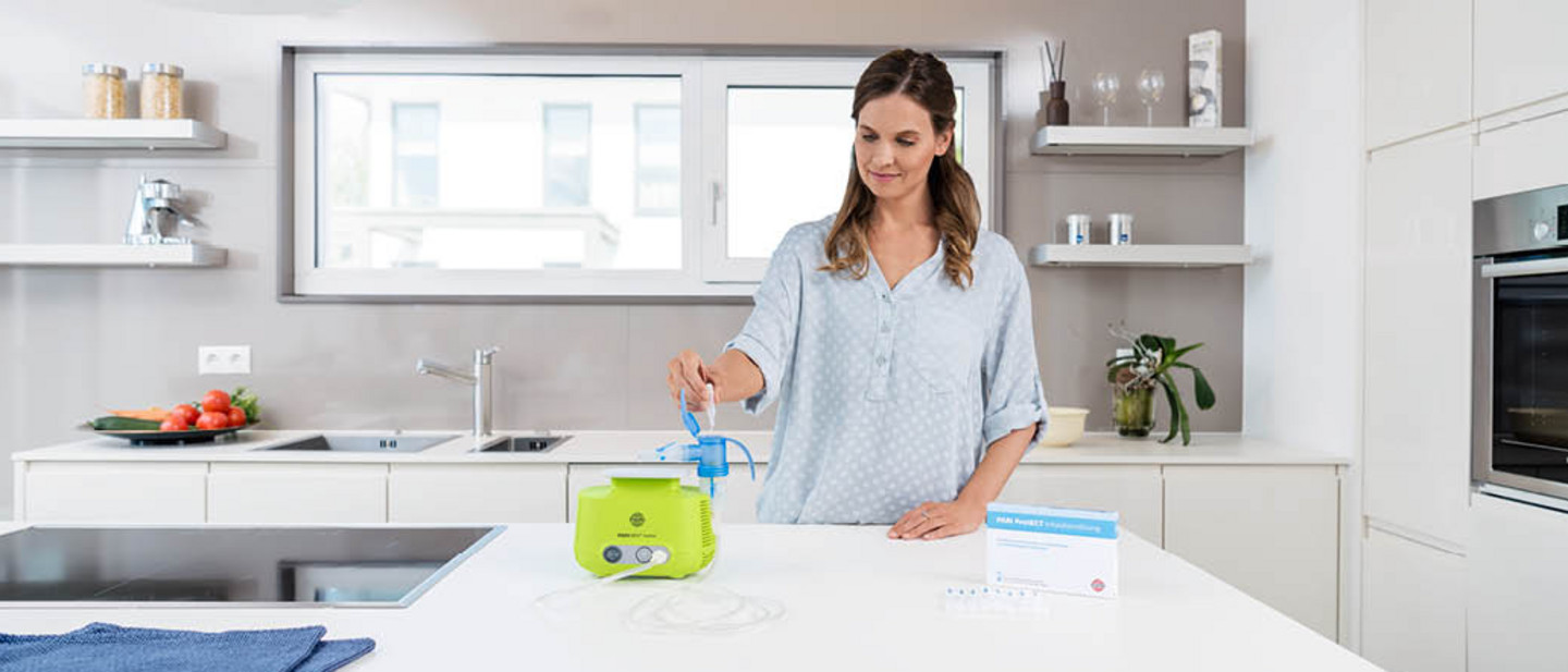 Befüllen eines Verneblers mit PARI Protect Inhalationslösung Eine Frau befüllt in einer modernen Küche den Vernebler eines PARI BOY Junior mit einer PARI Proect inhalationslösung.Eine Frau befüllt in einer modernen Küche den Vernebler eines PARI BOY Junior mit einer PARI Proect inhalationslösung.