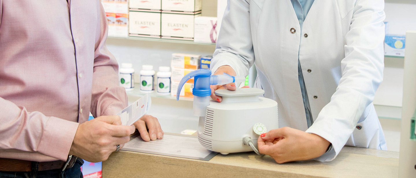 Eine Apothekerin klebt ein neues Garantielabel auf einen PARI BOY Kompressor