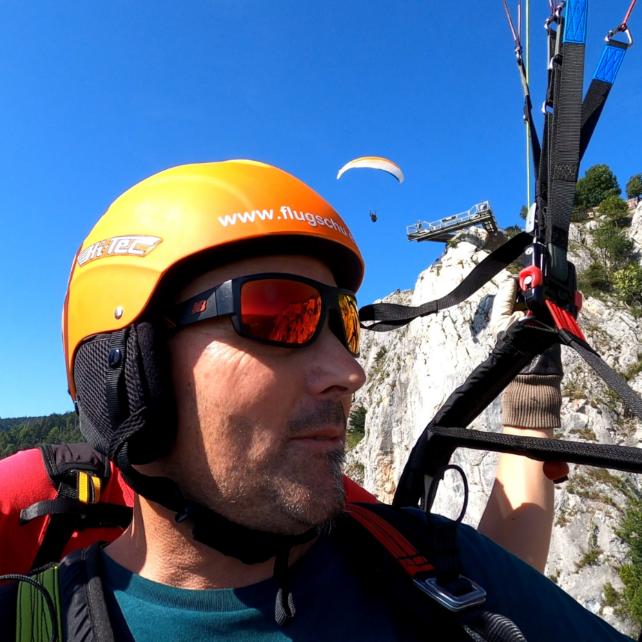 Halbnahaufnahme während eines Tandemflugs vom Fluggast im Schirm hängend, im Hintergrund ist der Skywalk zu erkennen
