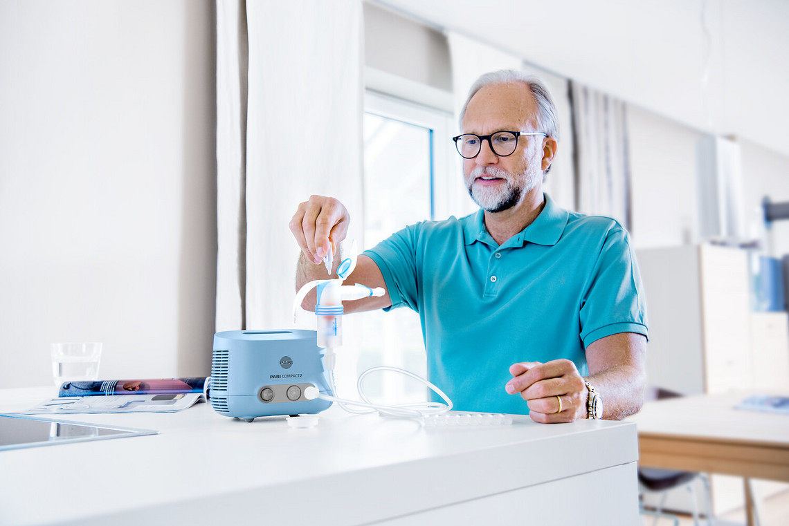 Elderly man filling the PARI COMPACT2 inhalation device with saline solution