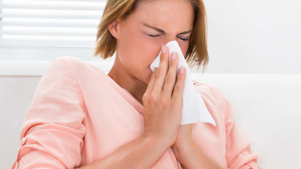 What you should do if you have a blocked nose because of an allergy: Helpful tips Frau sitzt auf Sofa und schnupft in ein Taschentuch, das sie mit beiden Händen vor ihre Nase hält