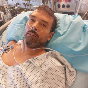 Mann liegt nach OP wach auf der Intensivstation an Geräte angeschlossen