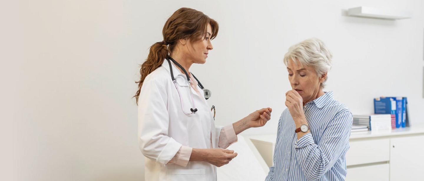 Doctor examining elderly woman with breathing difficulties in modern office, medical records and equipment in the background.