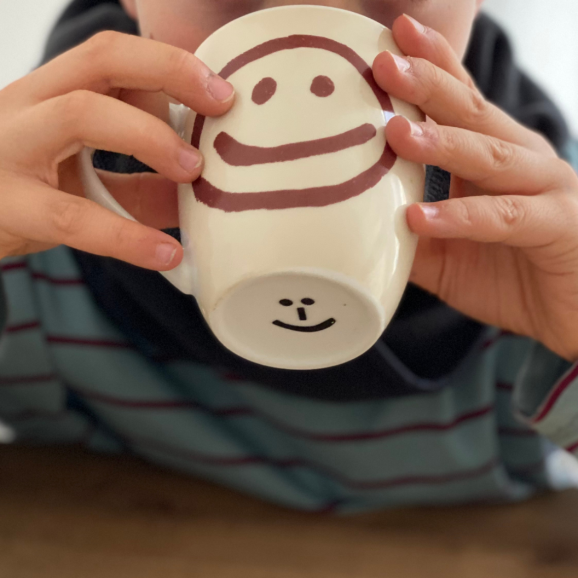 Home remedies against a cough: Drink herbal teas Child holds teacup in front of face and is drinking from it