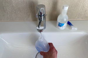 Nasendusche wird unter Wasserhahn gehalten und mit Leitungswasser aufgefüllt