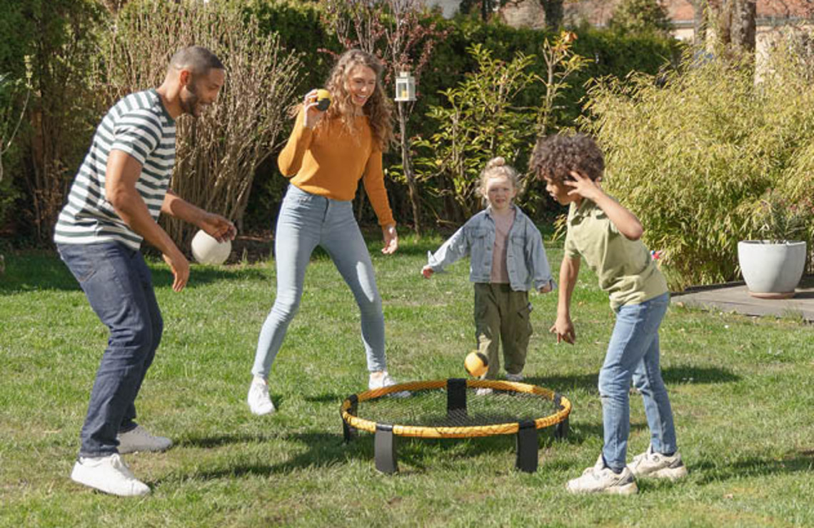 Group of people playing an outdoor ball game on a grassy lawn