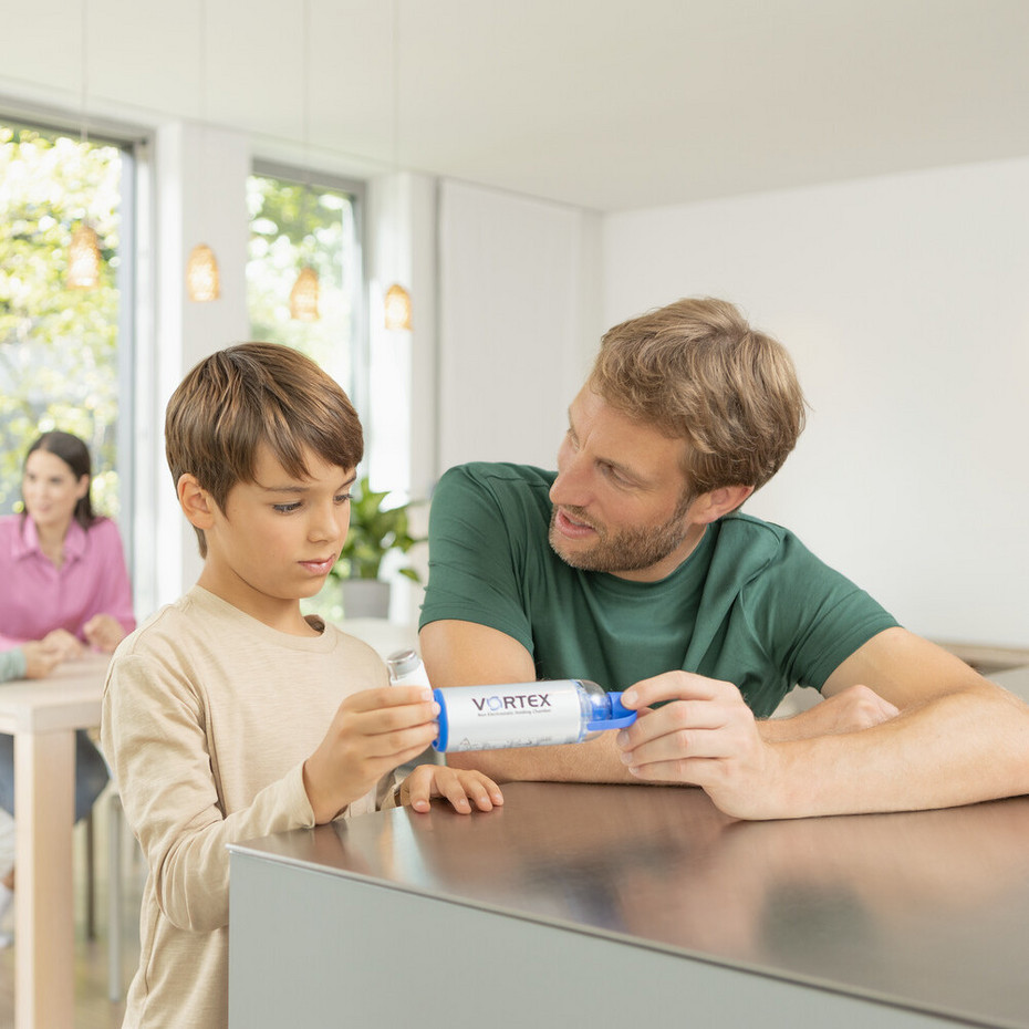 Vater und Sohn sitzen am Küchentisch und bauen die VORTEX Inhalierhilfe zusammen
