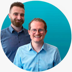 Two smiling men in a blue circle. The central man wears glasses and a light blue shirt. The man on the left has a beard and a blue patterned shirt.
