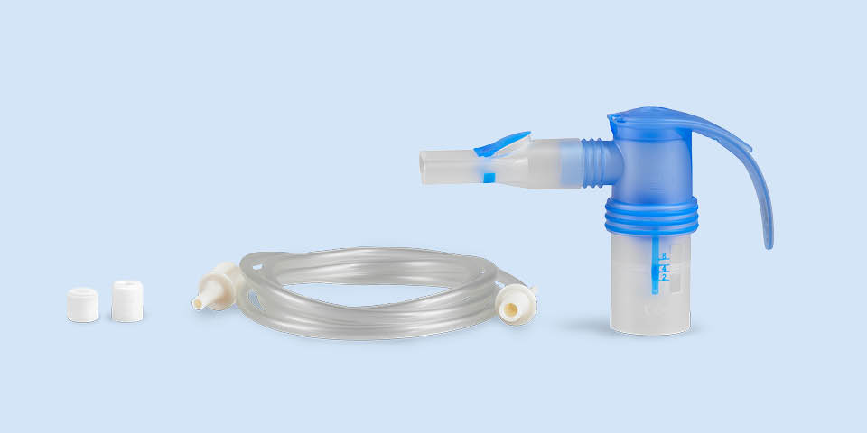 Produktabbildung: Vor einem blau-grauen Hintergrund steht rechts ein PARI LC SPRINT Vernebler mit Mundstück. Links daneben liegt der Anschlussschlauch, daneben zwei verschiedene Filtereinsätze für den Kompressor.