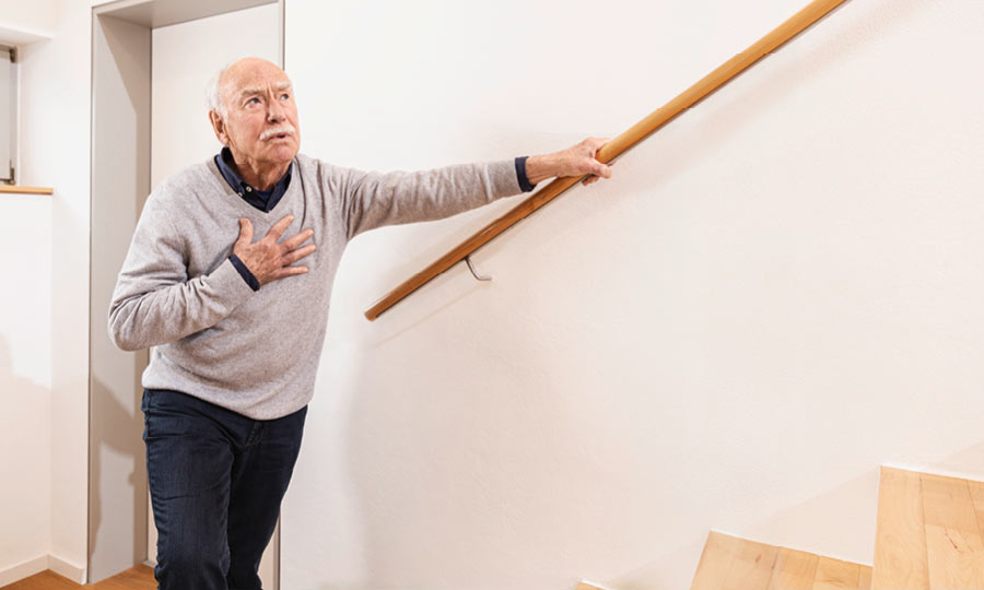 Ein Mann mit Bronchitis fasst sich beim Treppensteigen an die Brust 