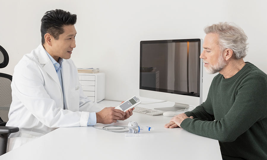 Ein Arzt erklärt seinem Patienten den PARI eFlow rapid und den eTrack Controller