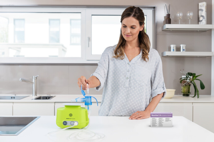 Woman fills inhalation solution into inhalation device in kitchen