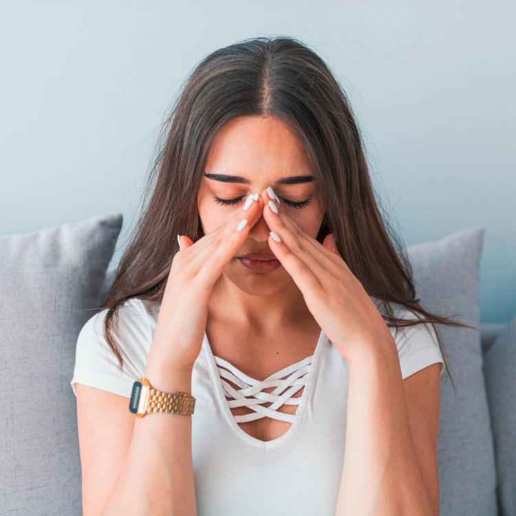 Woman grabs the top of her nose with both hands