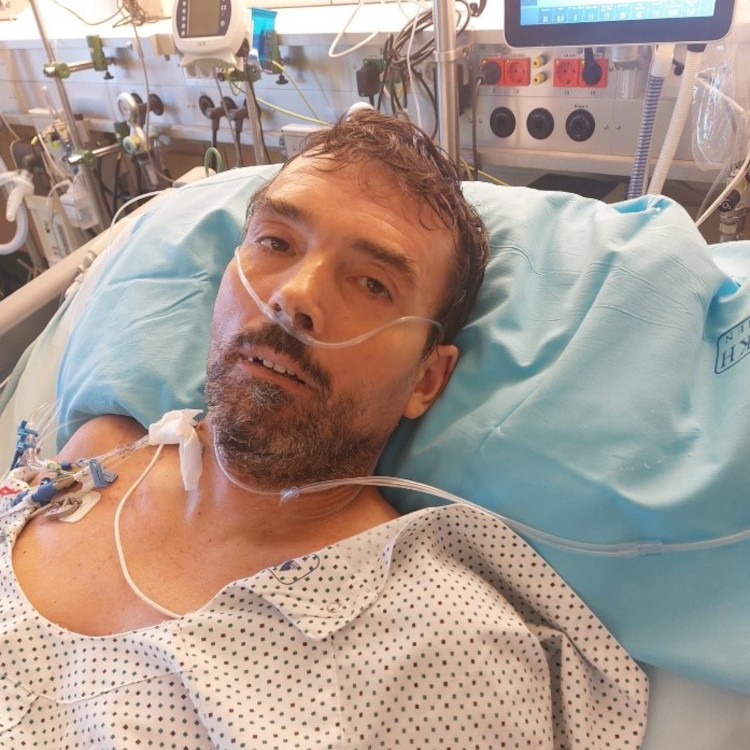 Mann liegt nach OP wach auf der Intensivstation an Geräte angeschlossen