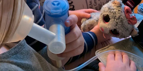 Ein Kind inhaliert und hat einen Teddy in der Hand