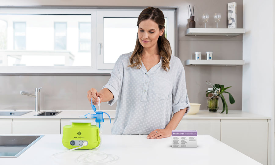 Frau steht in Küche und befüllt das Inhalationsgerät mit hypertoner Kochsalzlösung